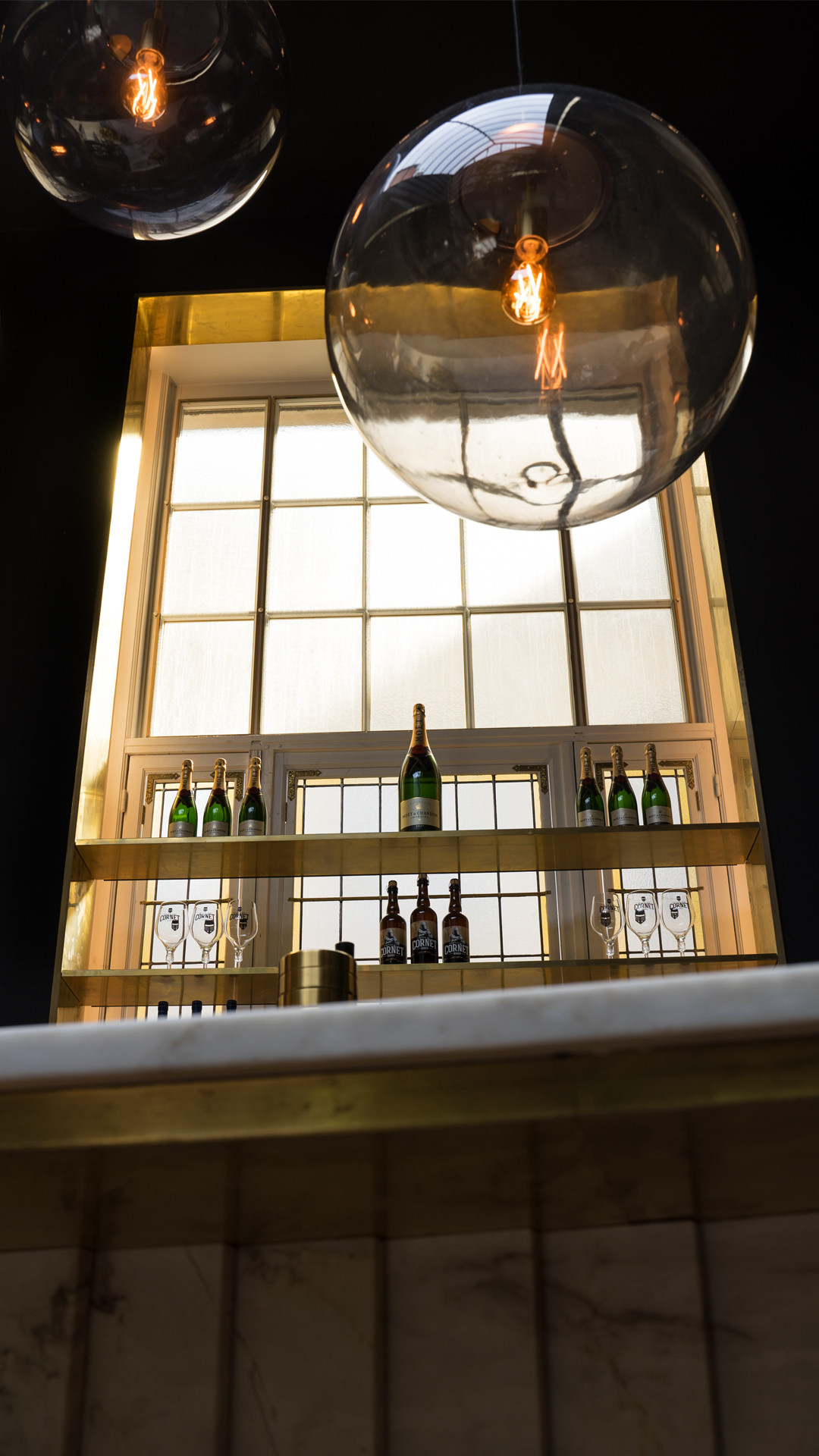 Une étagère en laiton avec des bouteilles de vin et des verres.